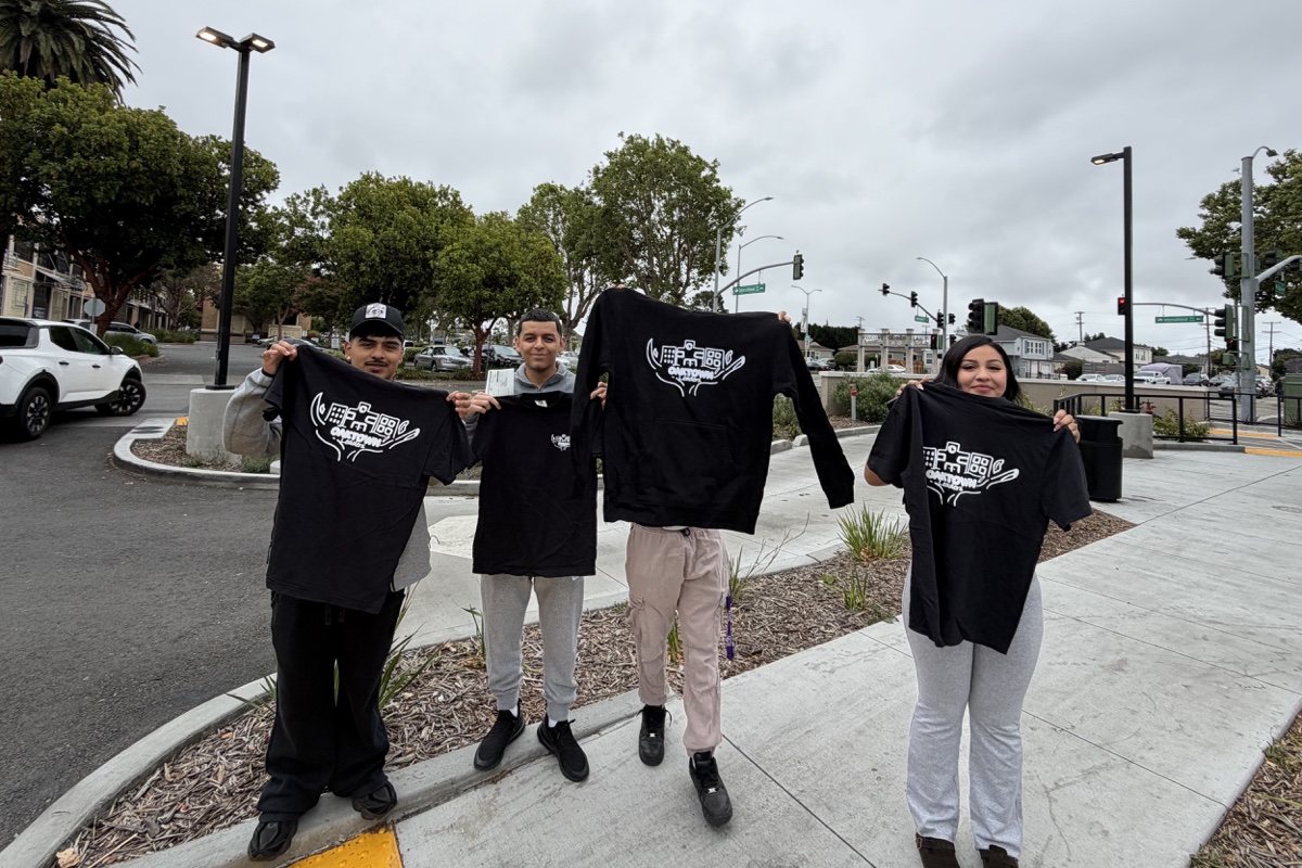 OakTown Leaders holding up their program shirts and sweatshirt together outdoors
